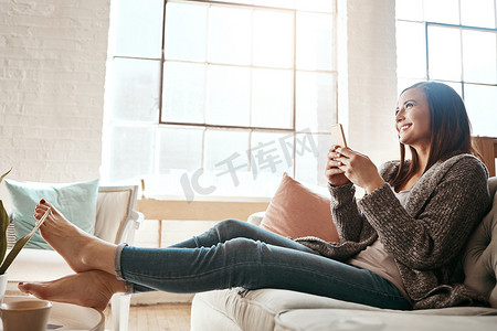 浏览摄影照片_互联网、电话和女人在家里的沙发上放松，使用社交媒体、发短信和浏览网页。