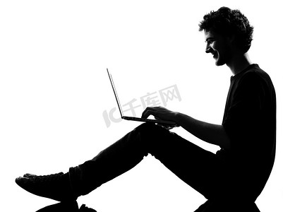 坐着计算笔记本电脑的年轻人剪影