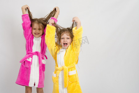 两个穿着浴袍的女孩扬起了湿漉漉的头发