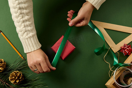女人的手包裹着圣诞礼品盒，特写。