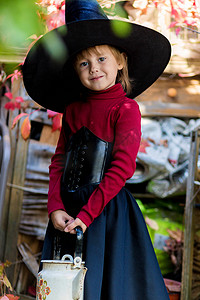 打扮成女巫的小女孩在万圣节派对上拿着水壶