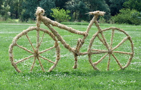 手工雕塑摄影照片_草坪上的稻草自行车雕塑