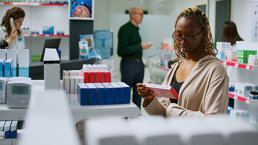 非洲裔美国妇女阅读维生素传单和检查药包