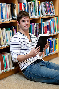 书店的人摄影照片_英俊的年轻人拿着一本书放在地板上