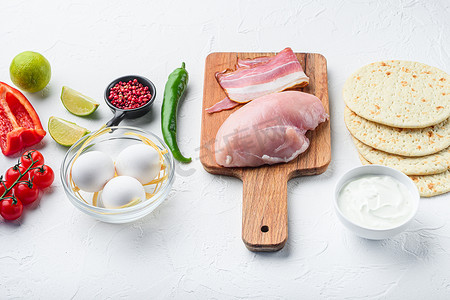 鸡肉炸玉米饼有机原料、西红柿、玉米、鸡蛋、胡椒、石灰鸡肉和玉米饼在白色带纹理的背景侧视图。