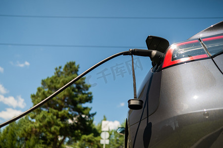 夏季在户外充电的黑色电动汽车。