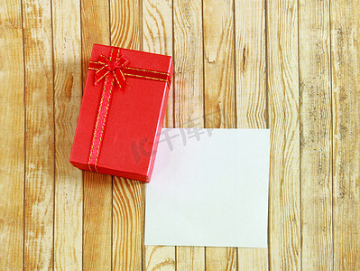 木制背景上带空白便条纸的红色礼物盒