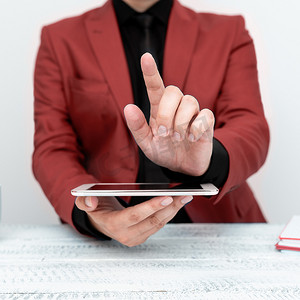 身穿红色夹克的商人坐在桌旁，手持手机，用一根手指指着重要信息。