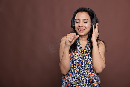 戴着耳机微笑的印度女人，用想象中的麦克风唱歌