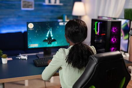 职业玩家女性坐在游戏桌前玩太空射击游戏
