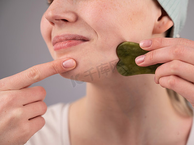 一位年轻女子用水粉刮刀按摩脸部的特写肖像。