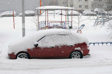 雪带来的红色汽车停在院子里。