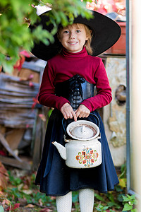 打扮成女巫的小女孩在万圣节派对上拿着水壶