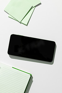 桌上贴纸摄影照片_手机屏幕上有重要的想法，并在带有笔记本和记号笔的办公桌上贴着便条。