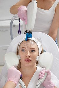 医学美容摄影照片_几位医生的手拿着激光设备在女性脸上的概念美容和美容图像。