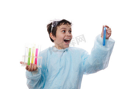 化学实验室穿着摄影照片_穿着实验室大衣的聪明书呆子少年，拿着装有化学品和试剂的试管，看着发生的化学反应