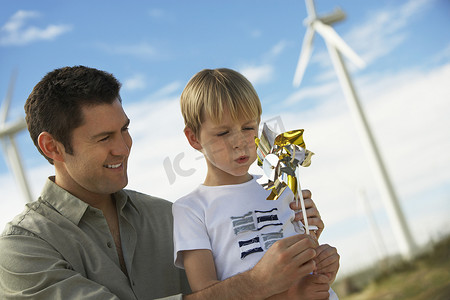 可爱的小男孩和父亲在风电场吹玩具风车