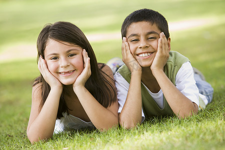 两个小孩在户外躺在公园里微笑
