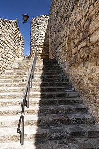 近邻摄影照片_阳光明媚的日子里，16 世纪堡垒旁边的石阶，西班牙安达卢西亚哈恩省 Sabiote 街