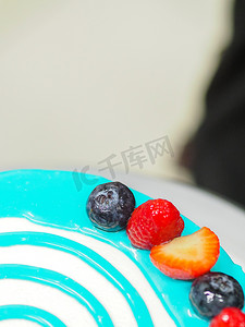 手工糕点师设计师在磨砂白蛋糕上浇上浅蓝色滴灌袋