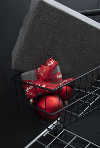 黑纸圣诞礼盒放在带红球的购物篮里