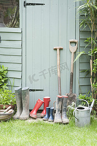 花园棚旁的黑桃、耙子和惠灵顿靴子