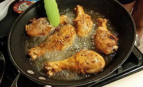 鸡腿拉面摄影照片_在煎锅中用热油烹饪的鸡腿