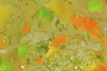 水背景中蔬菜的特写视图，包括胡萝卜、豌豆、花椰菜、玉米、切碎的土豆和欧芹。