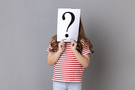 身份不明的小女孩穿着条纹 T 恤站在纸后面躲着脸，上面有问号。