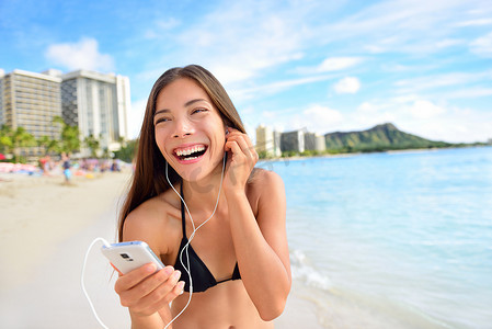 在智能手机上听音乐的快乐海滩女人