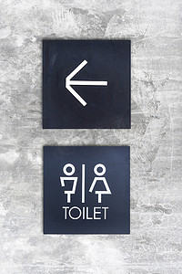 箭头标志摄影照片_混凝土墙式精品店上的男女通用厕所或厕所和箭头标志