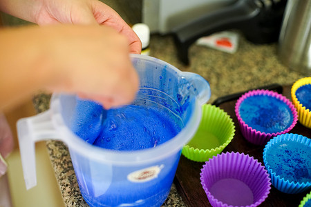 硅胶模具摄影照片_在塑料杯中融化肥皂并添加颜色和香料，然后倒入彩色硅胶模具中，制作自制的融化和倒肥皂