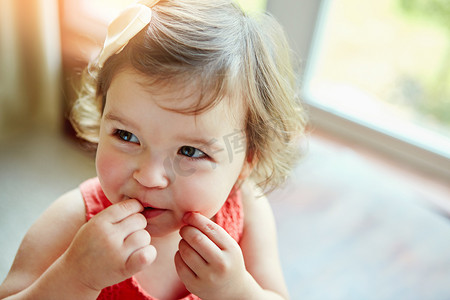 快乐、婴儿和女孩在她家里玩耍，一边咬着她的手一边看、尝和好奇。