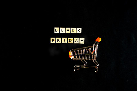 黑色星期五用黑色背景上的木字书写，带有购物篮、销售、假日销售、顶视图、平面布局、降价