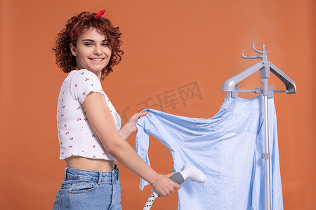 一个脸上带着微笑的女人用蒸笼熨男人的衬衫。