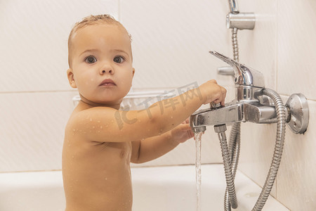 婴儿在浴室洗澡时手握水龙头