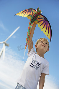 国潮风龙摄影照片_一个可爱的小男孩在风电场玩龙风筝的低视角
