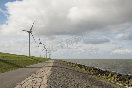 绿色草风车摄影照片_荷兰堤坝附近的现代风车