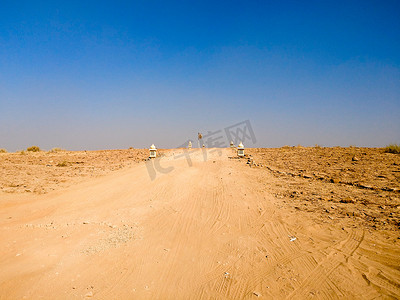 空荡荡的土路，两边都是荒芜的沙漠，上面是蓝天，上面是印度拉贾斯坦邦的塔尔沙漠