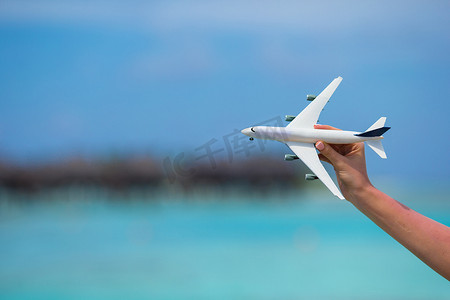 在绿松石海背景的小的白色玩具飞机