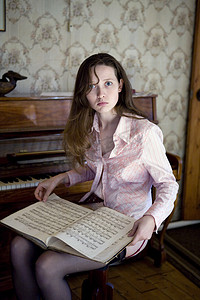 蓝色可爱风摄影照片_坐在钢琴上的年轻女子