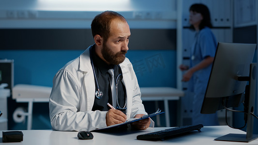 全科医生在电脑上检查医疗报告与纸上写的专业知识比较