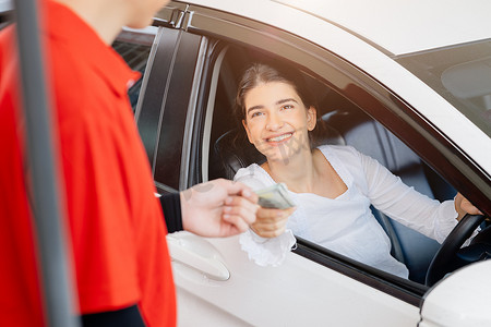 司机客户通过信用卡向工作人员支付燃油费用，让他们在加油站开心地微笑。