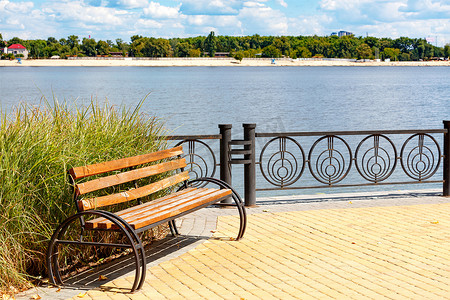 在宽阔的河流和模糊的沙滩背景下，第聂伯河堤岸上的一张木凳。