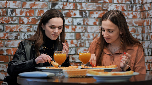 互相喂食摄影照片_年轻女孩在咖啡馆吃饭，互相喂食。