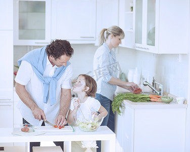 父亲和女儿在厨房里准备健康的饭菜时互相看着对方