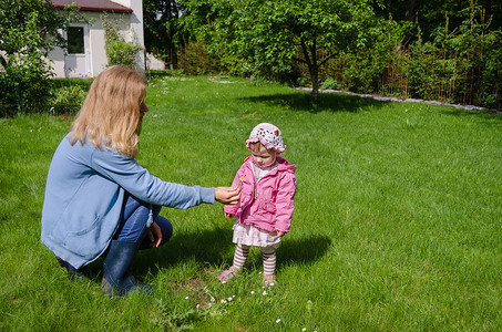 妈妈坐在草地上女儿采菊花