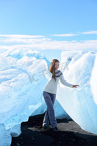 冰山摄影照片_Jokulsarlon 冰山海滩的冰岛游客在冰海滩上的冰山上行走。 