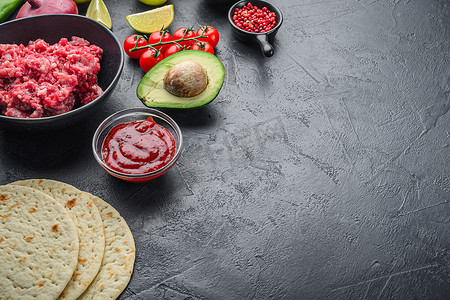 传统的墨西哥玉米饼混合了配料、玉米、肉、蔬菜、莎莎酱、黑色纹理背景上的酱汁、带有文本空间的侧视图。