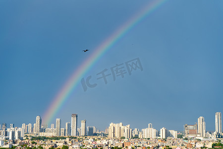 钳子古达摄影照片_季风日古尔冈德里诺伊达建筑物的空中城市景观照片，背后有彩虹